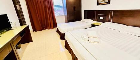 Habitación de hotel con dos camas, un escritorio, un armario y una ventana con cortinas.