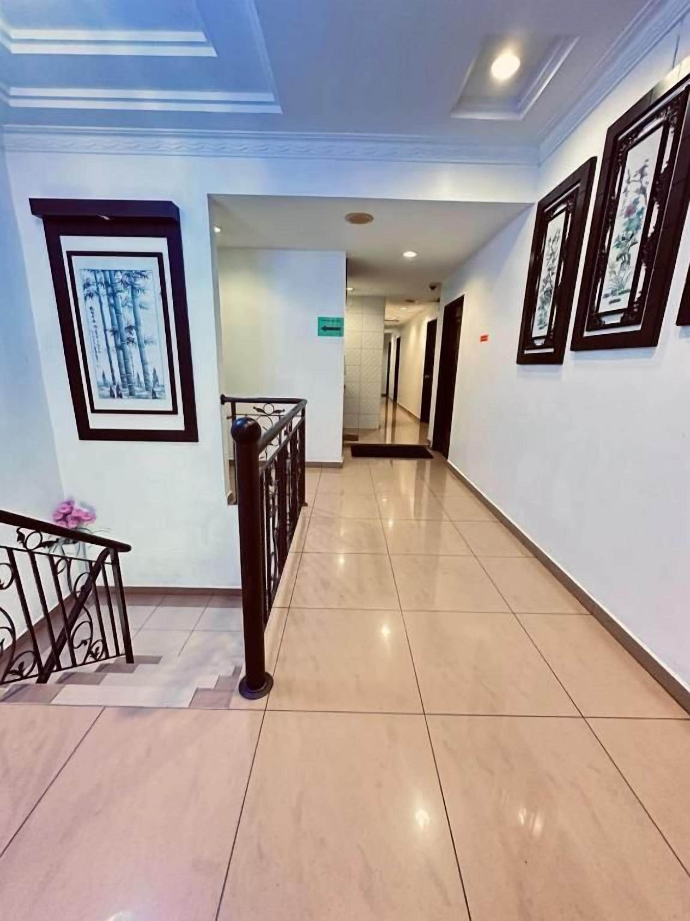 A hallway with a tiled floor, a handrail, and framed artwork on the walls.