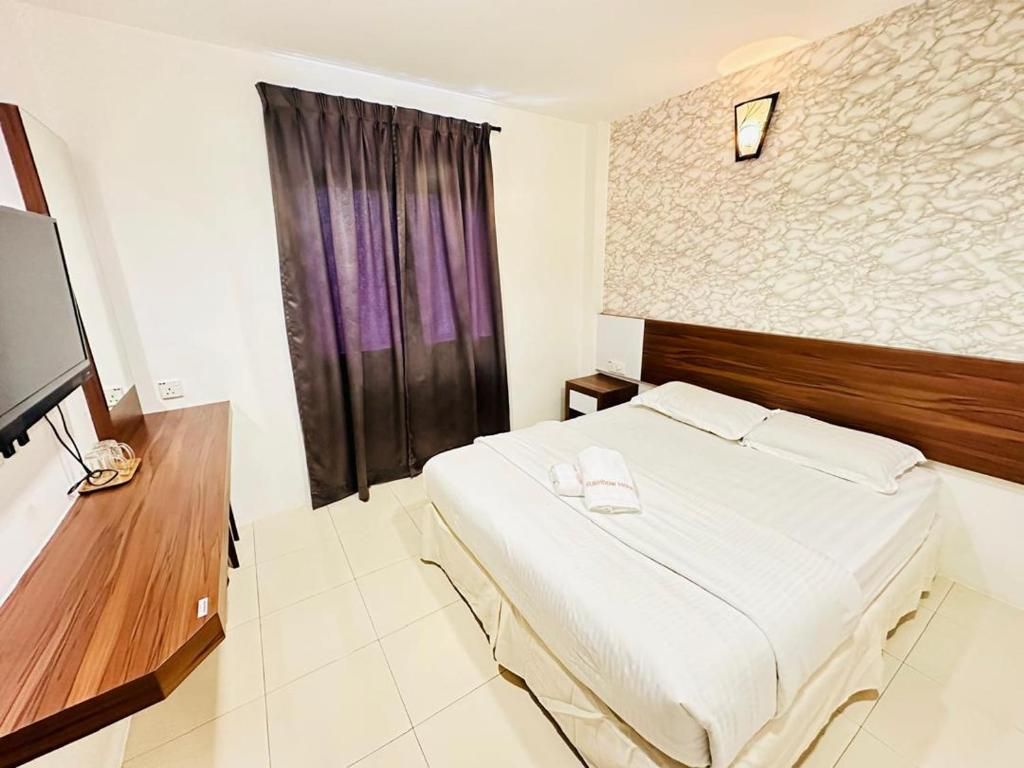 A hotel room with a bed, a wooden desk, a television, and a window with curtains.