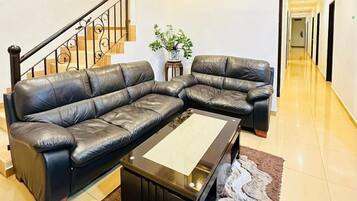 A modern living room with a leather sectional sofa, a coffee table, and a staircase.