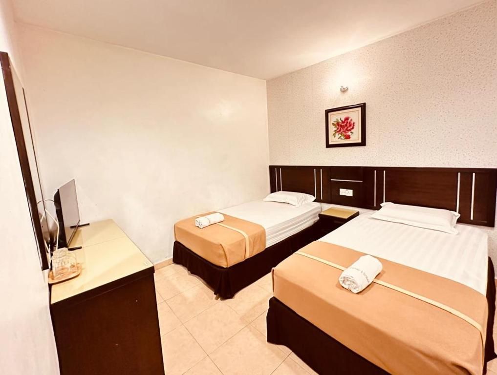 A hotel room with two beds, a desk with a computer, and a framed picture on the wall.