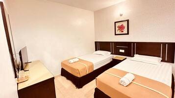 A hotel room with two beds, a desk with a computer, and a framed picture on the wall.