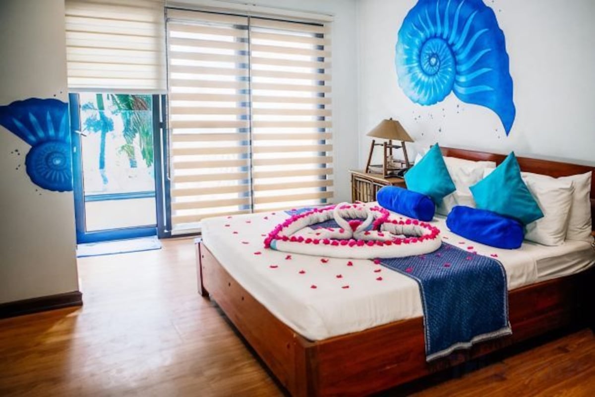 Une chambre à coucher avec un lit, des oreillers, une couverture et un objet décoratif posé sur le lit.