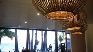 A restaurant with large windows overlooking the beach, featuring wicker pendant lighting and wooden furniture. - 357 Boracay (Boracay Island)