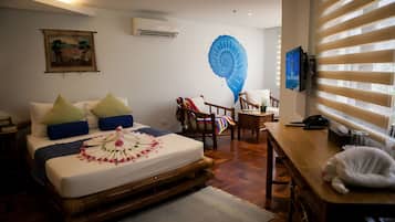 A bedroom with a bed, a desk, a chair, and a television.