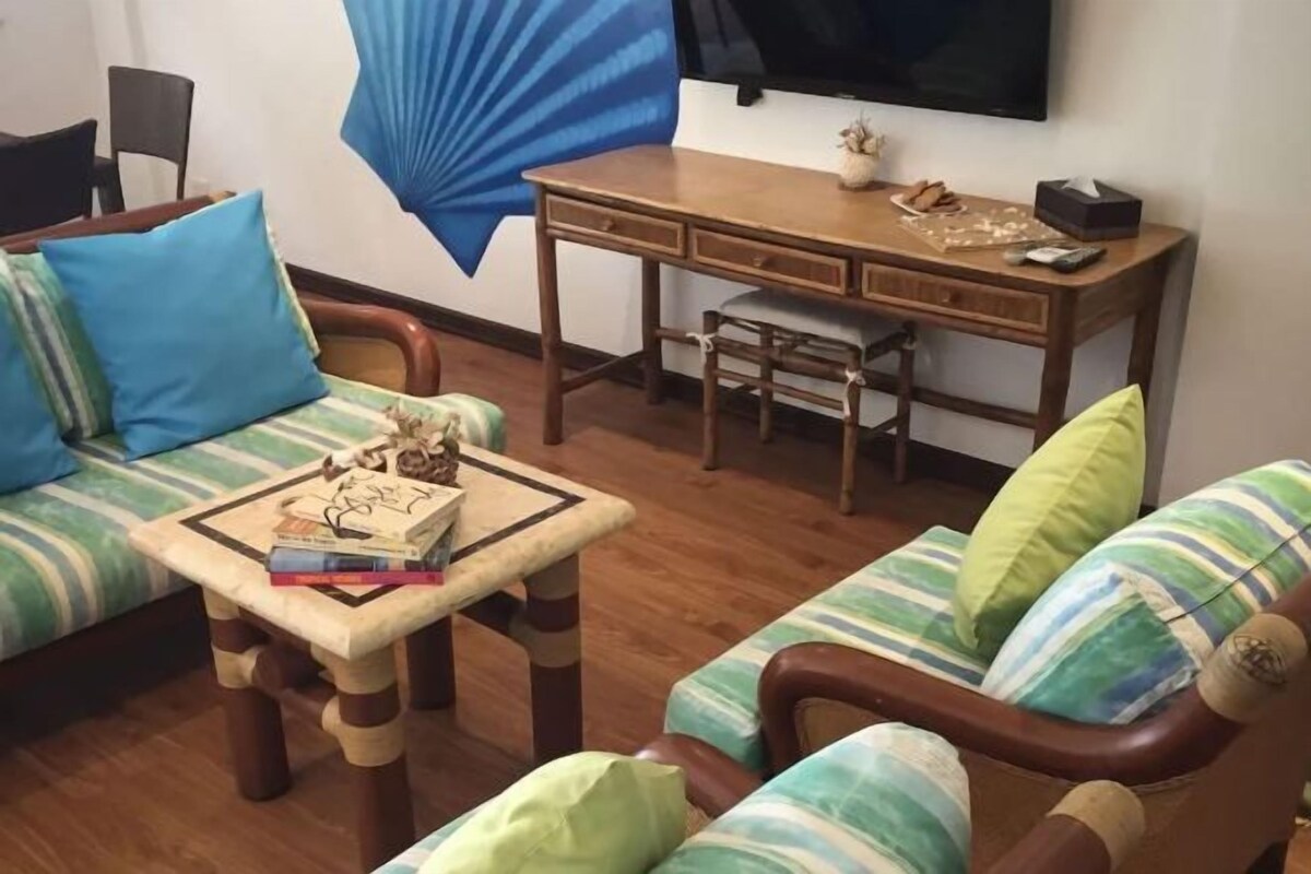 A living room with a sofa, a wooden coffee table, a desk, and a television.
