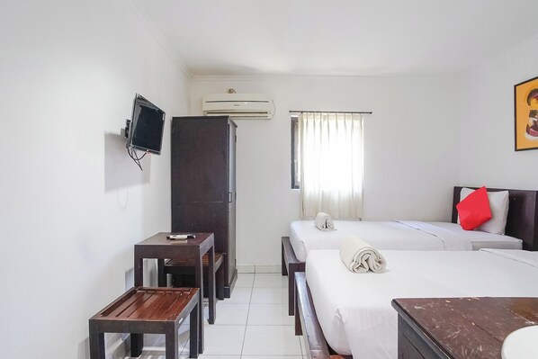 A hotel room with two beds, a desk, a TV, and an air conditioner. - Gana Inn Legian (Kuta)