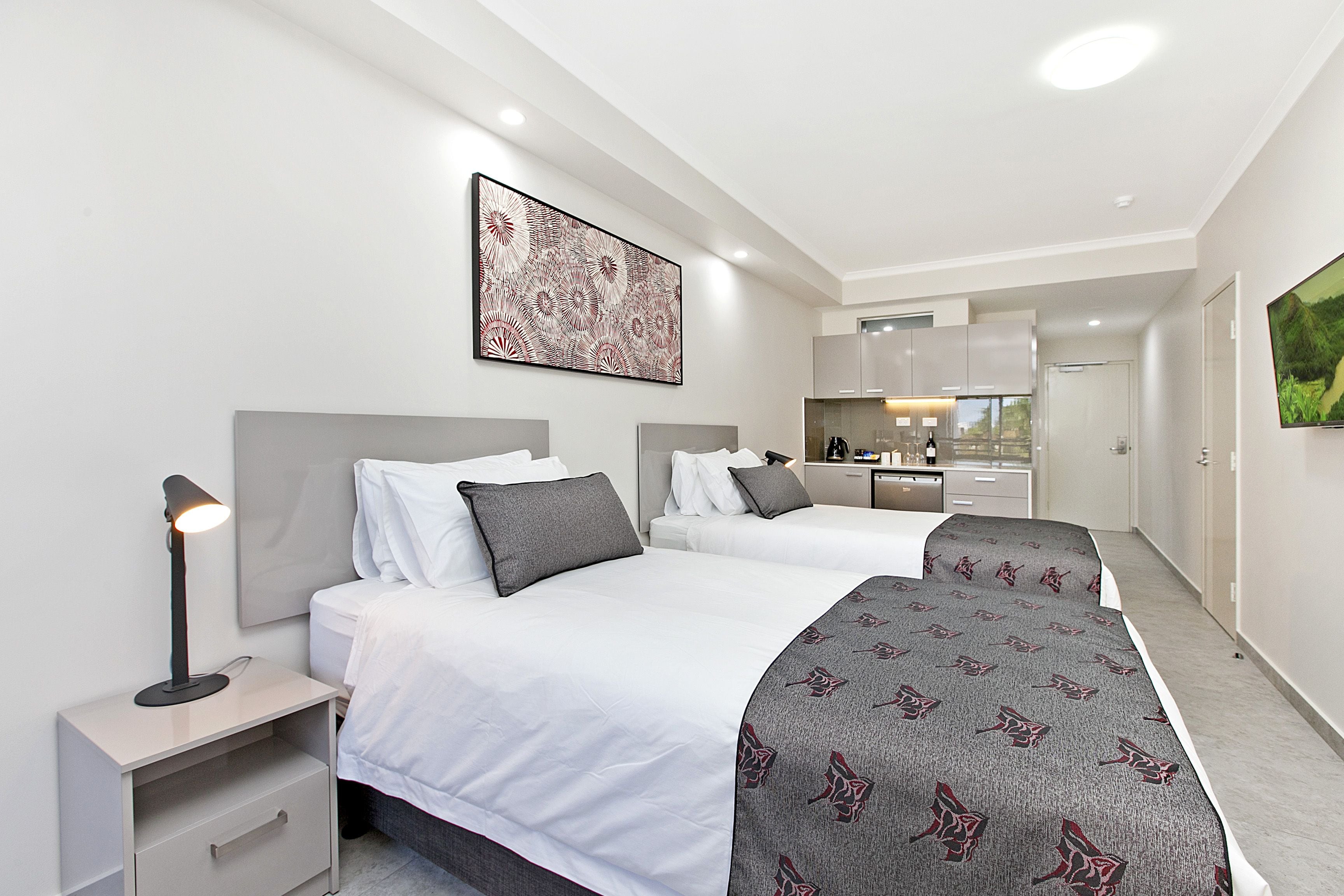 A modern hotel room with two beds, a desk, a nightstand, and a large window.