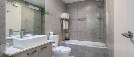 Un baño moderno con lavamanos, inodoro y ducha.