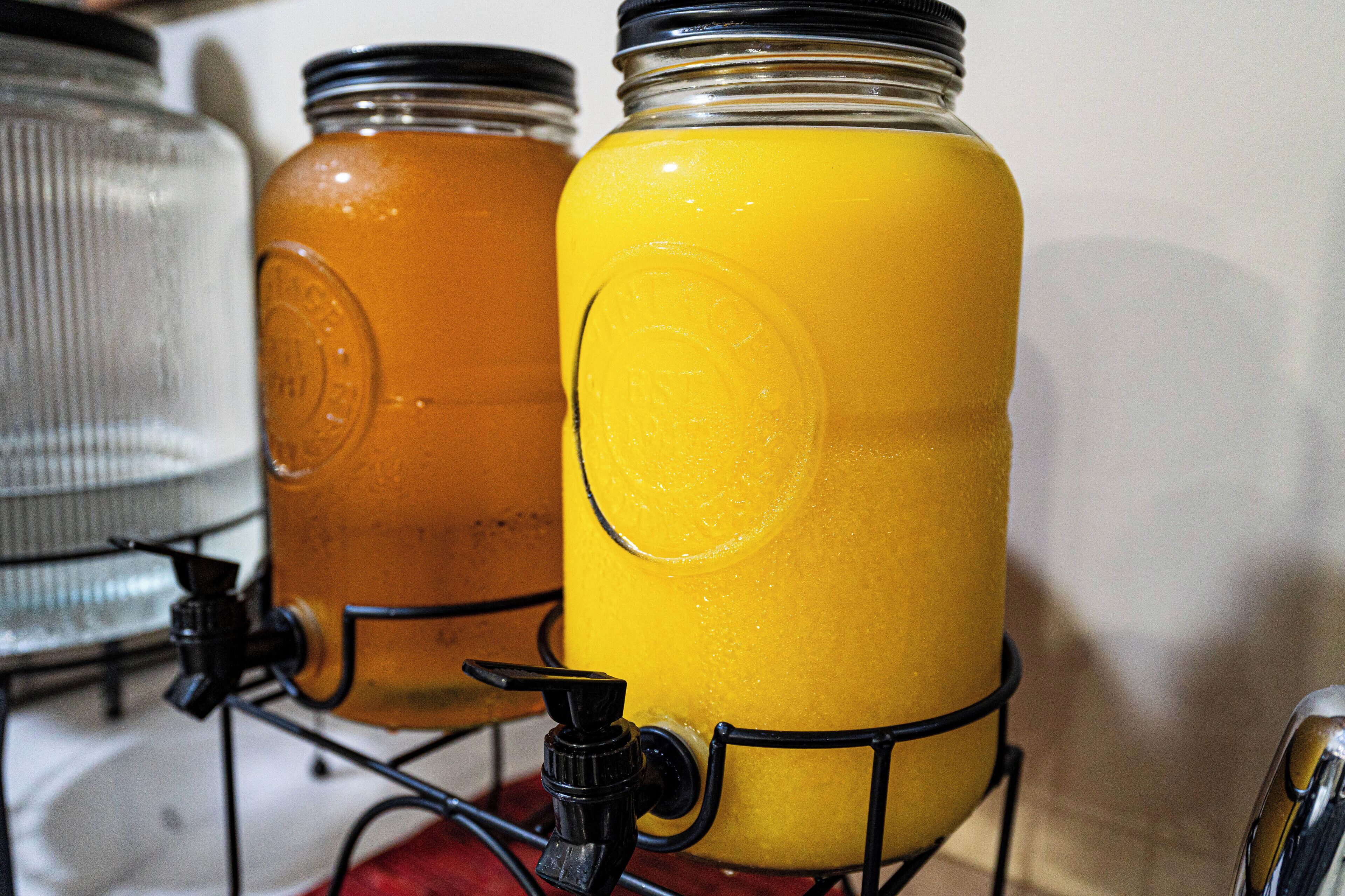Two glass containers with metal lids, one with a yellow liquid and the other with a clear liquid, both on a metal stand.