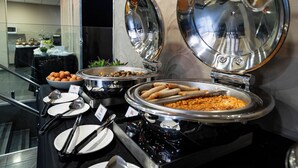 Una barra de buffet con distintos alimentos y utensilios para servir.