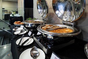 Una barra de buffet con distintos alimentos y utensilios para servir.