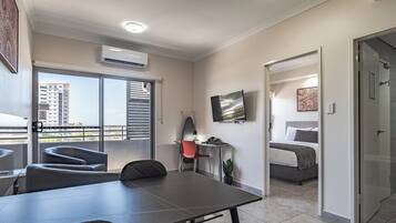 A modern hotel room with a balcony, a dining area, and a bedroom.