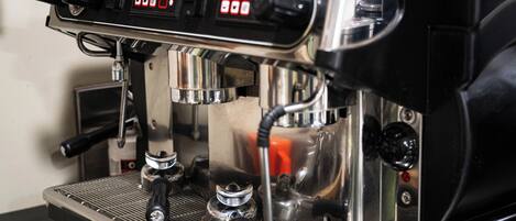 A close-up of an espresso machine with a digital display, steam wand, portafilter, and portafilter basket.
