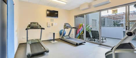 A fitness room with treadmills, a stationary bike, and a wall-mounted TV.