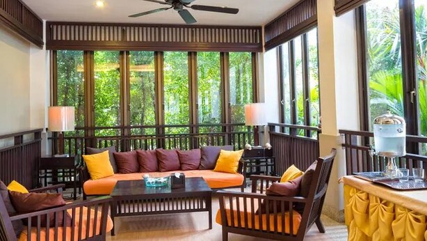 Una habitación amplia con un ventanal grande, un ventilador de techo y una mesa con sillas.