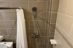 A bathroom with a shower, toilet, and a towel rack. - Panya Resort Hotel (Udon Thani)