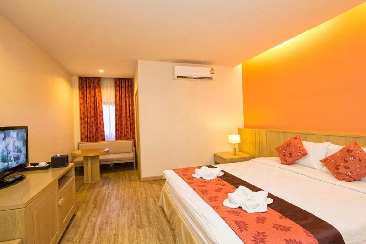 Quarto de hotel com cama, televisão, escrivaninha, cadeira e ar condicionado.
