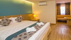 Una habitación de hotel con una cama, una mesita de noche con lámpara, un sofá y una pequeña mesa redonda.