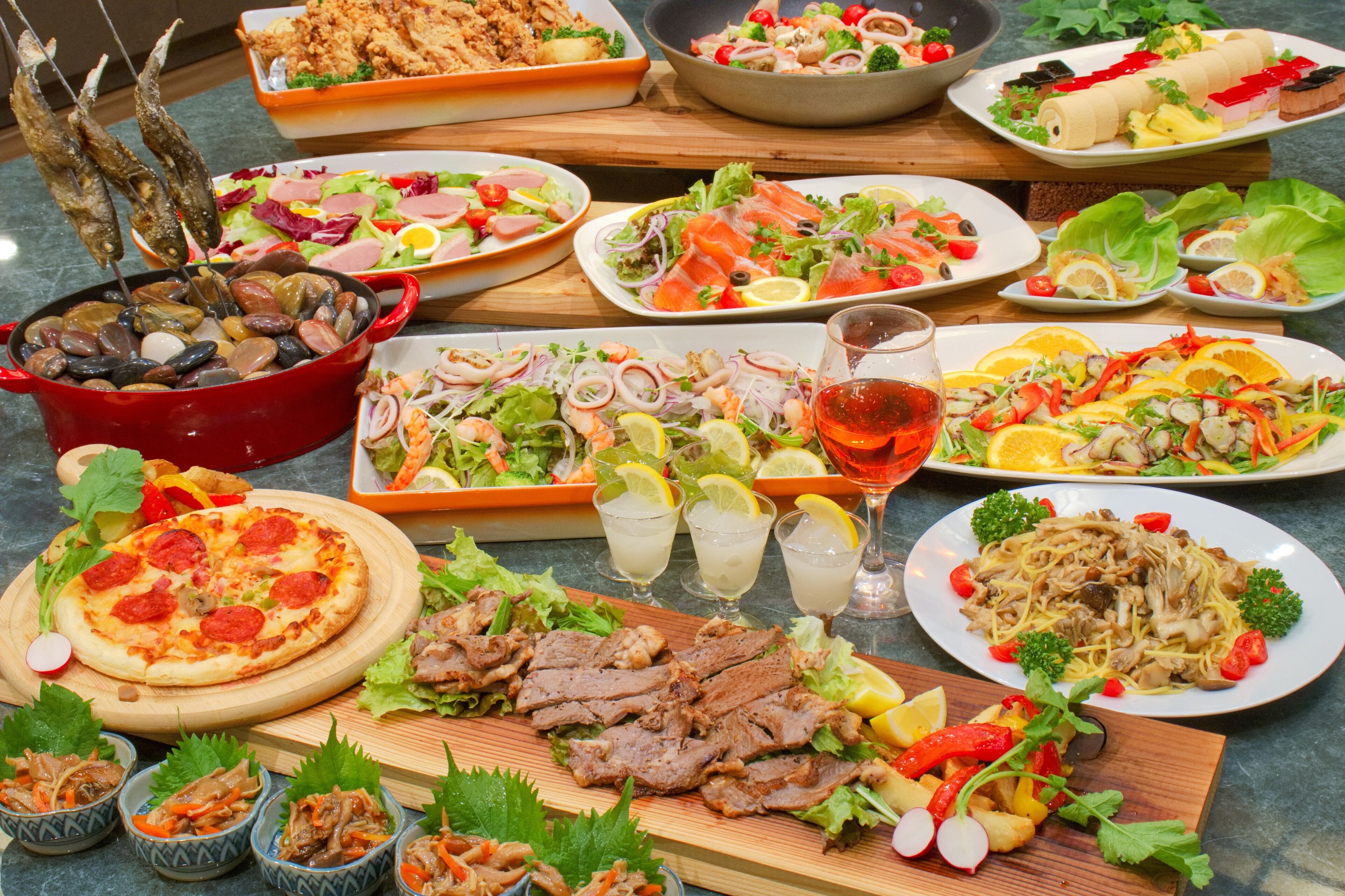 Variedad de platos que incluyen mariscos, ensaladas y pizza, lo que sugiere un menú diverso.