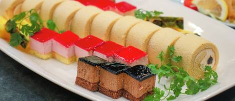 A dessert platter with various sweets and a roll of pastry, garnished with parsley.