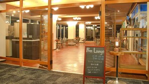 Een restaurant met een glazen scheiding, houten inrichting en een krijtbord waarop staat aangekondigd: gratis lounge uren.