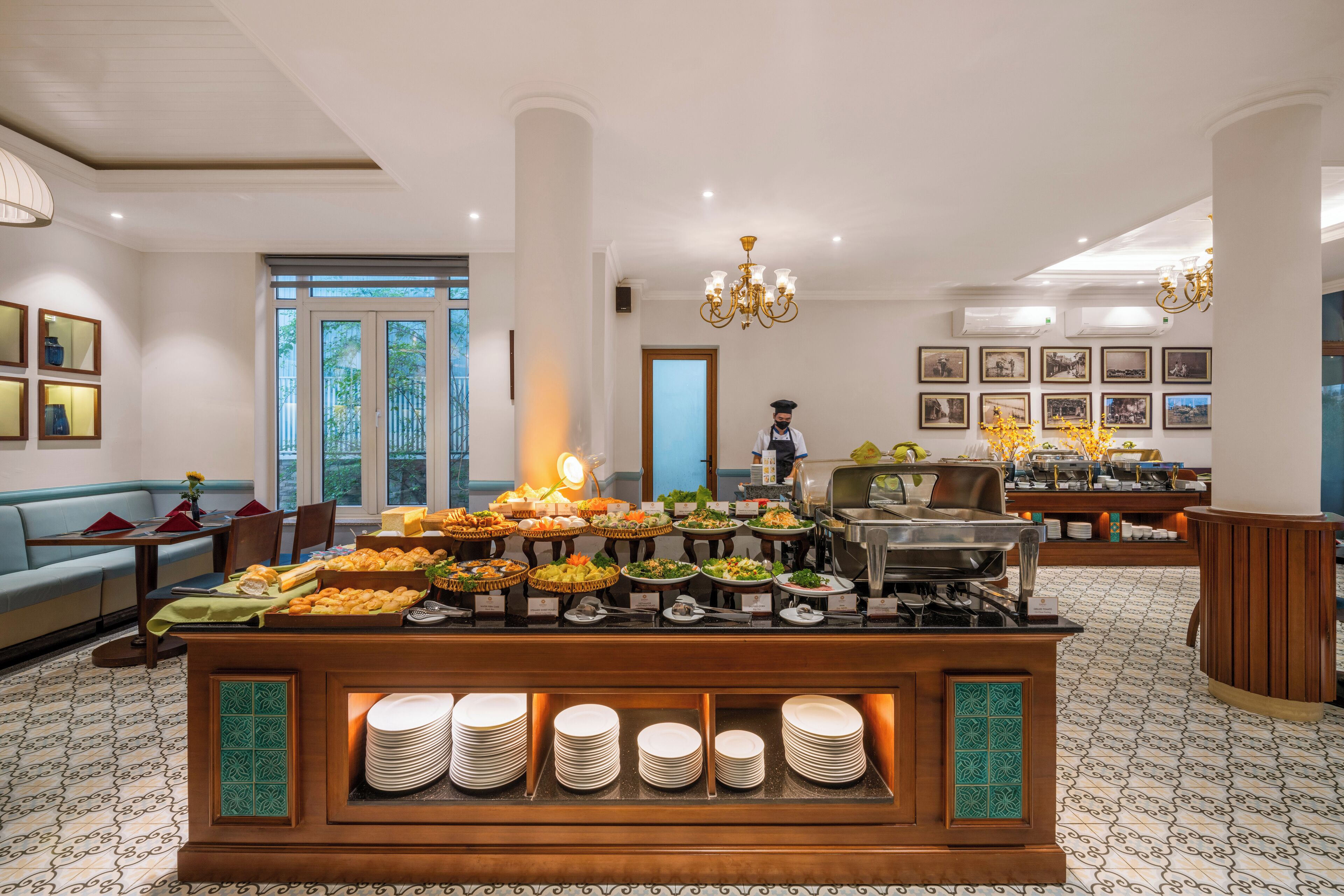 A buffet setup with various food items and a staff member in the background.