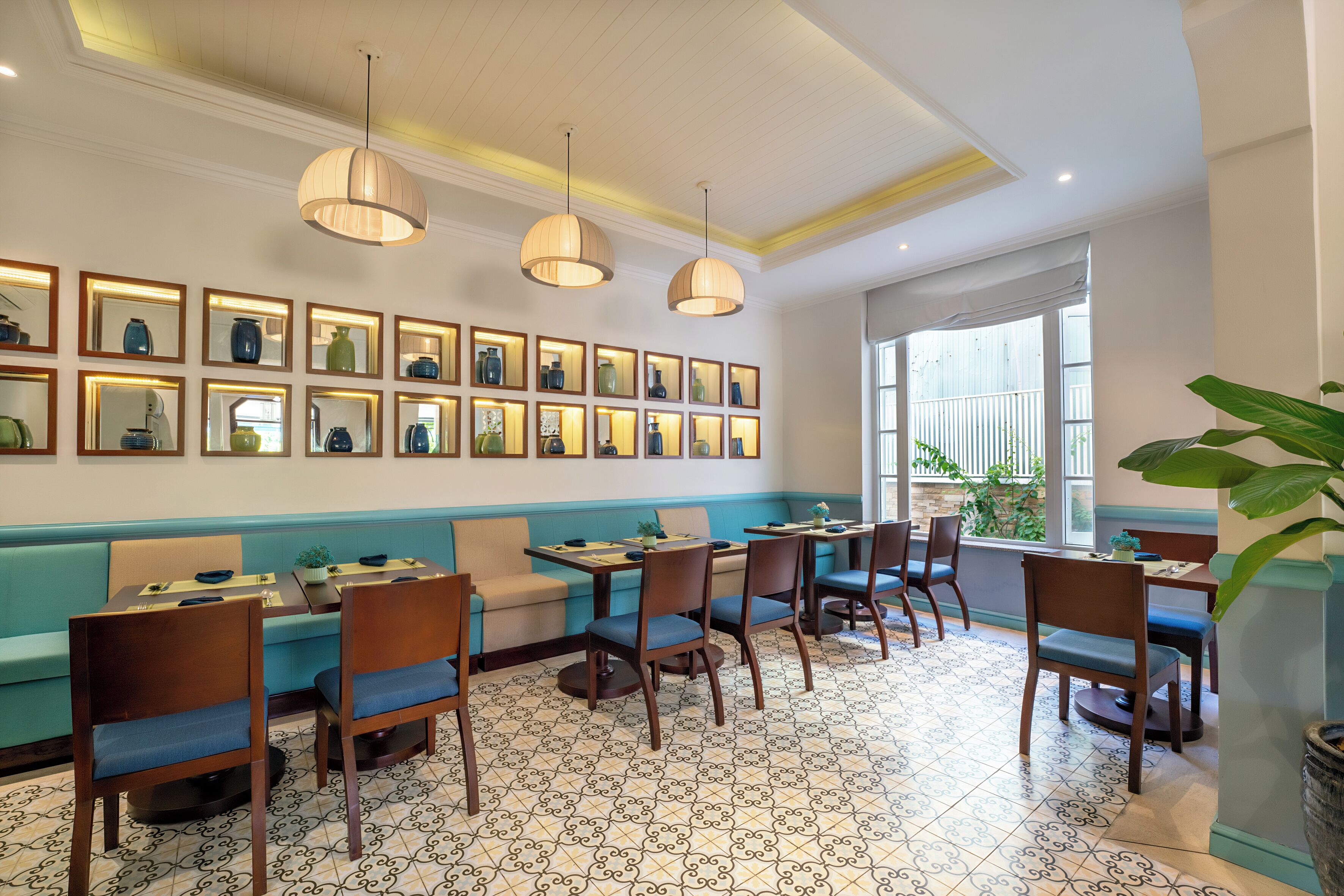 A restaurant with a blue and white tiled floor, wooden tables and chairs, and pendant lighting.