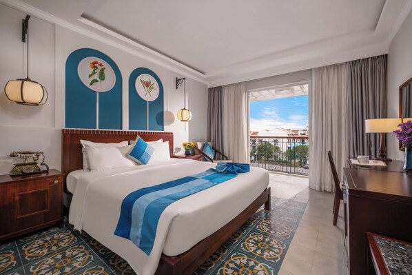 Een hotelkamer met een groot bed, een bureau, een stoel, een balkon met uitzicht en een decoratieve wand.