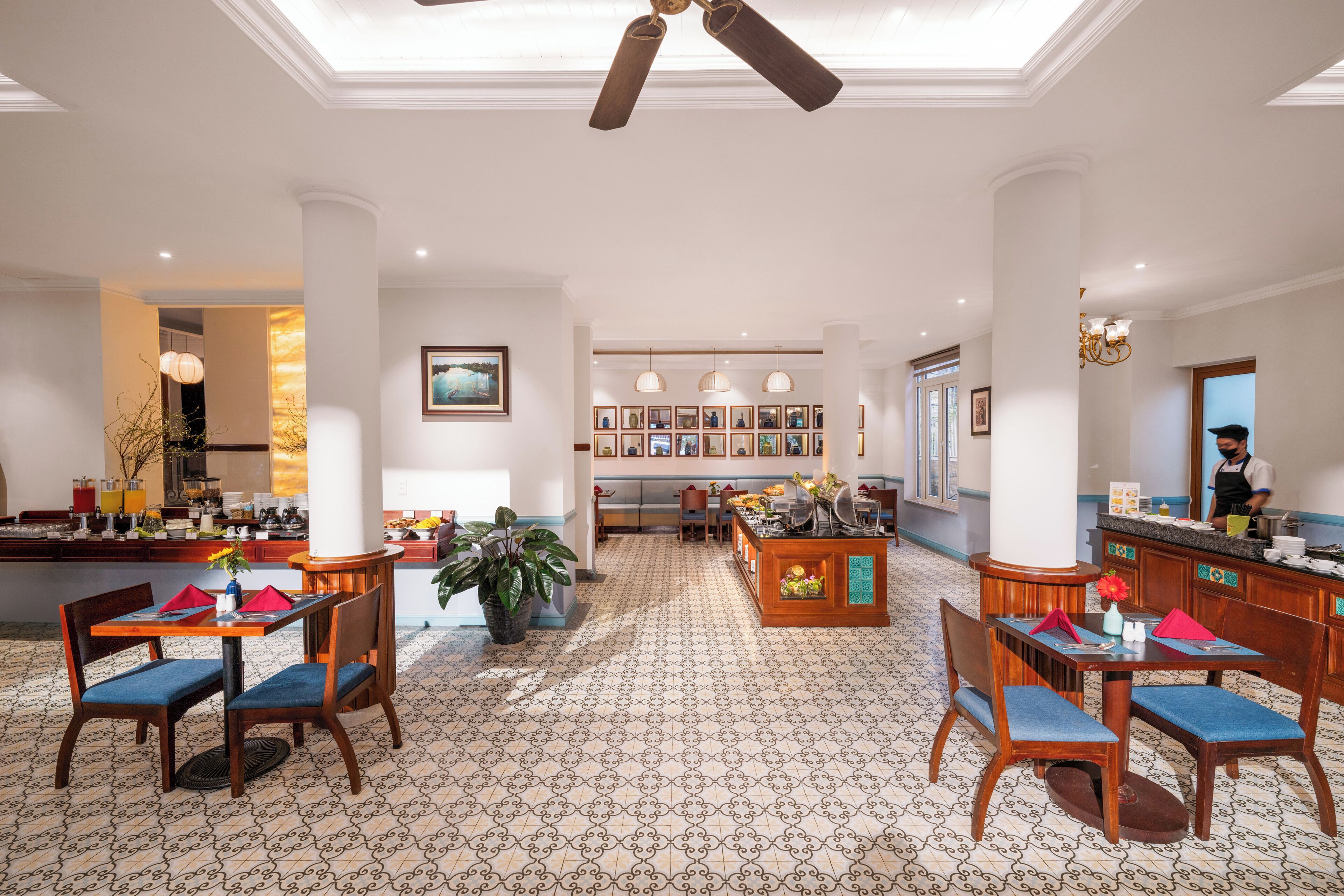 Un hall d'hôtel avec un espace salon central, un comptoir d'accueil et une cuisine en arrière-plan.