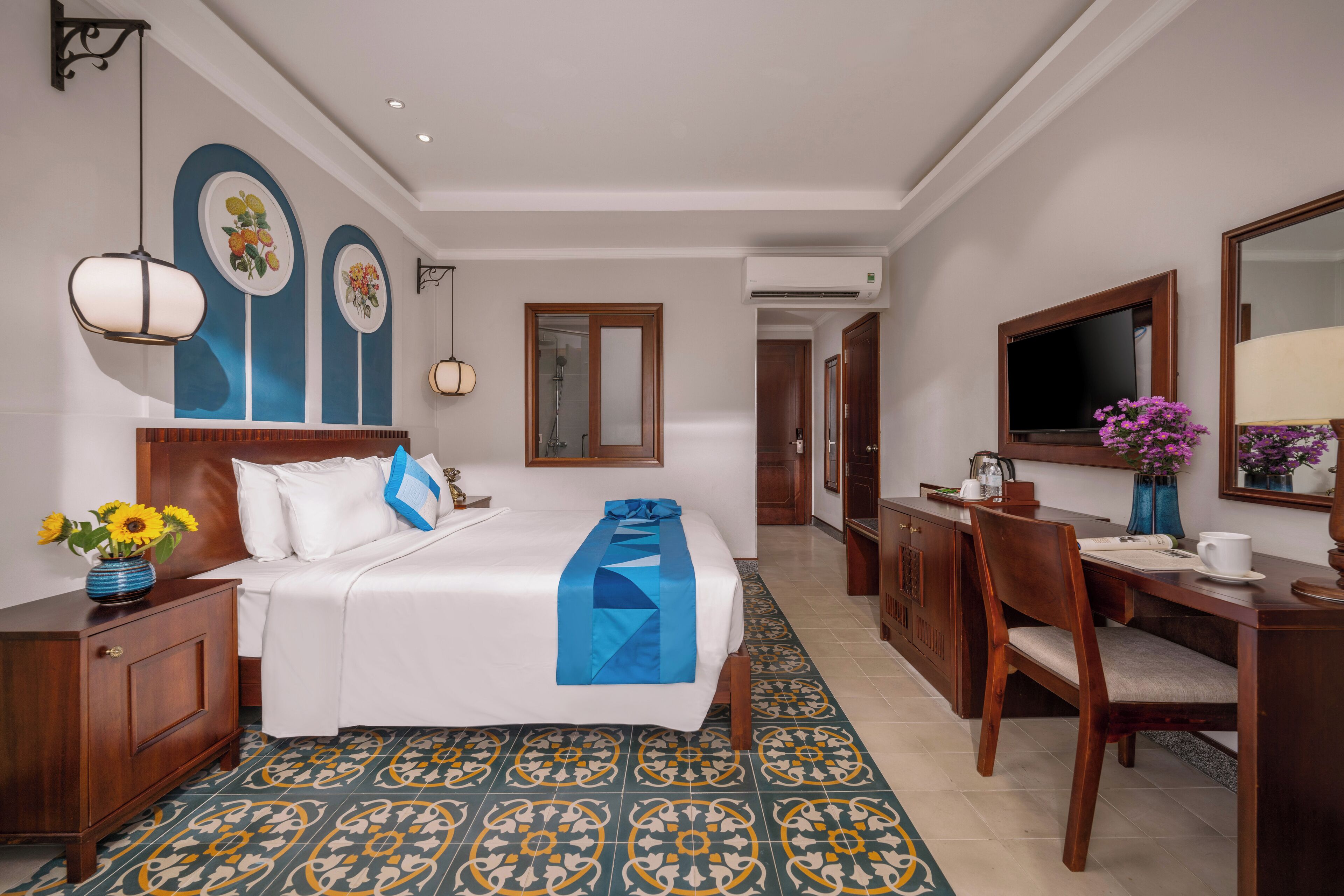 A hotel room with a bed, bedside table, dresser, desk, and a TV.