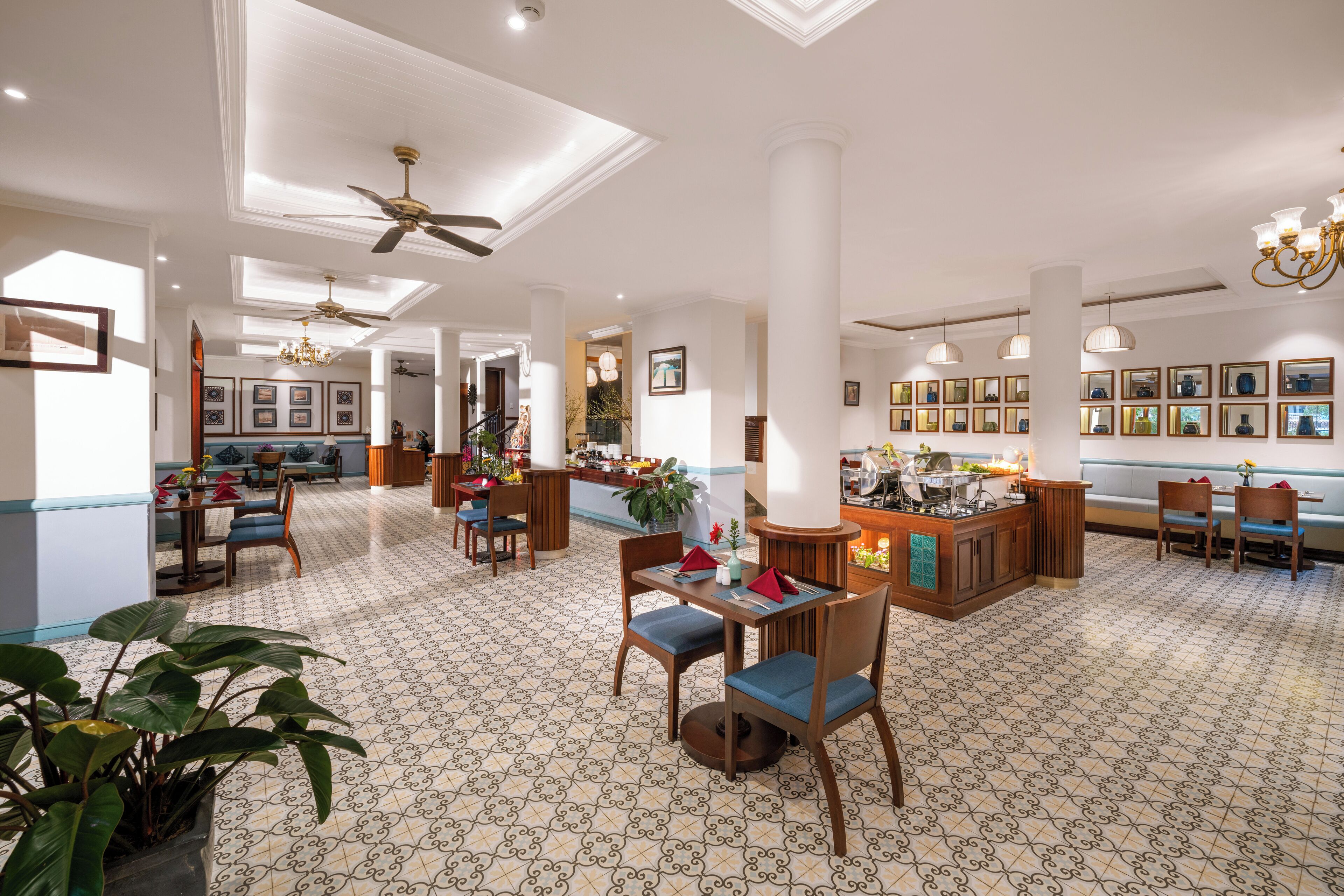 A spacious hotel lobby with a patterned floor, multiple seating areas, and a central bar.