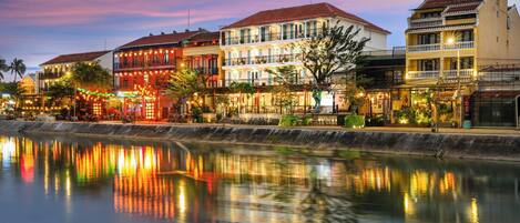A waterfront hotel with multiple stories, balconies, and a reflection in the water.
