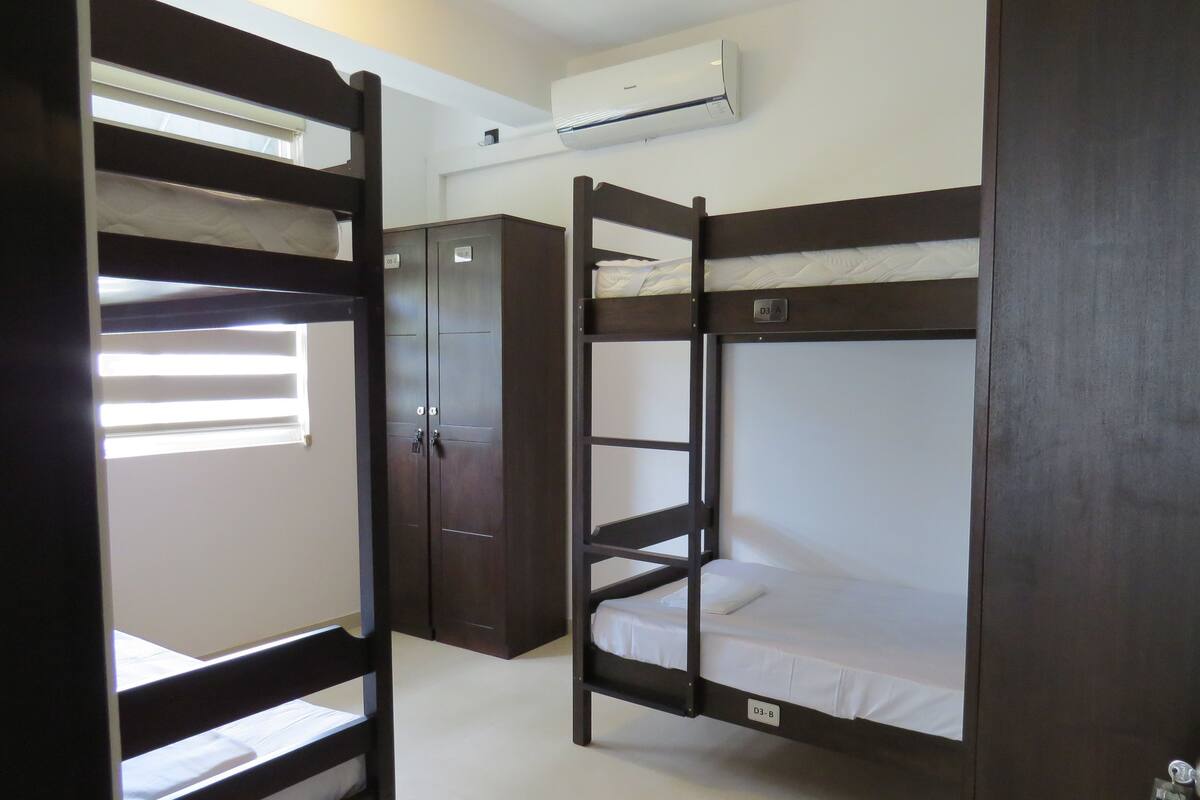 A room with bunk beds, a wardrobe, and an air conditioning unit.