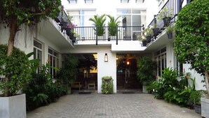 A courtyard with a paved ground, surrounded by potted plants and trees. - Chapelton House (Colombo)