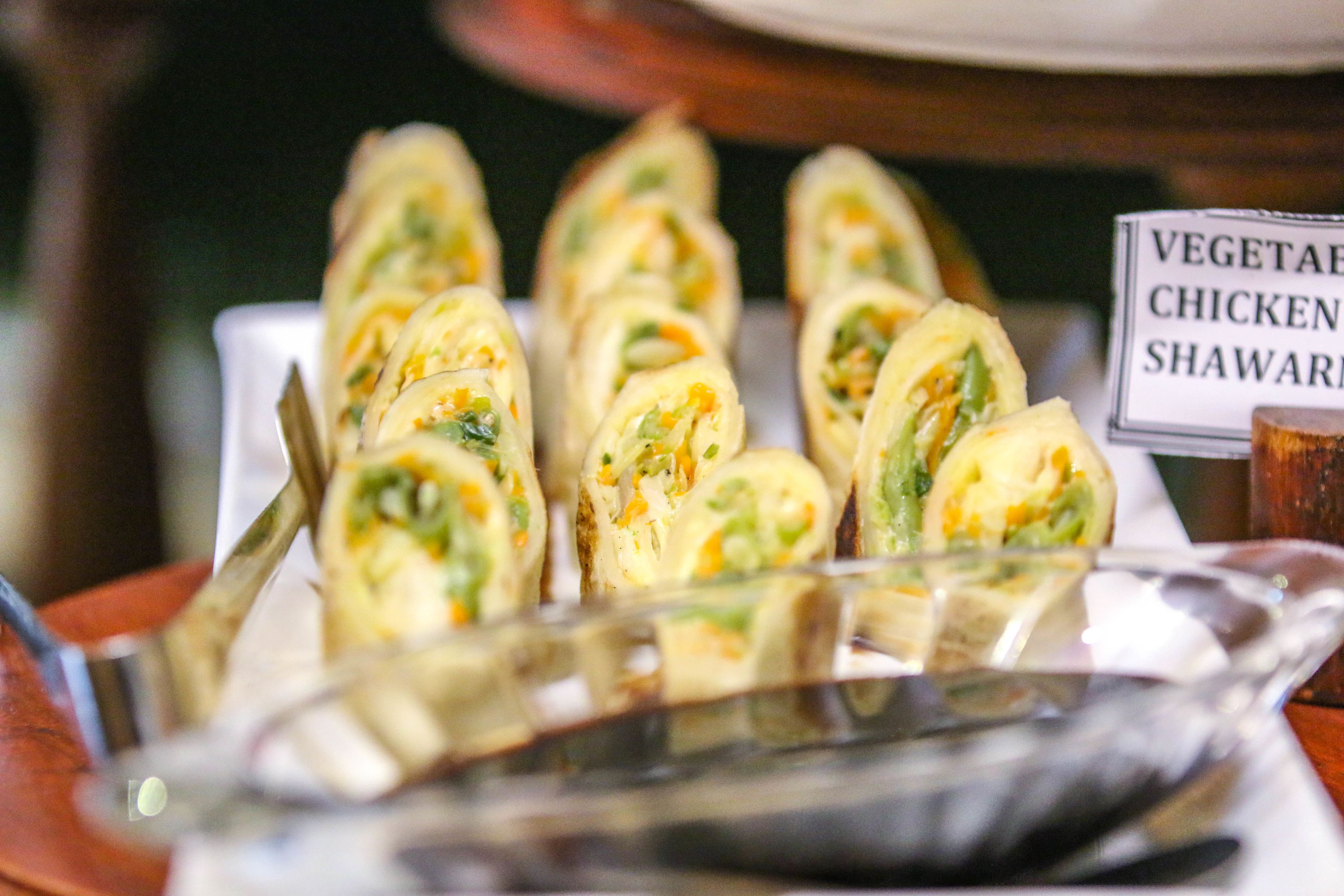 A tray of vegetable, chicken, and shawarma wraps.