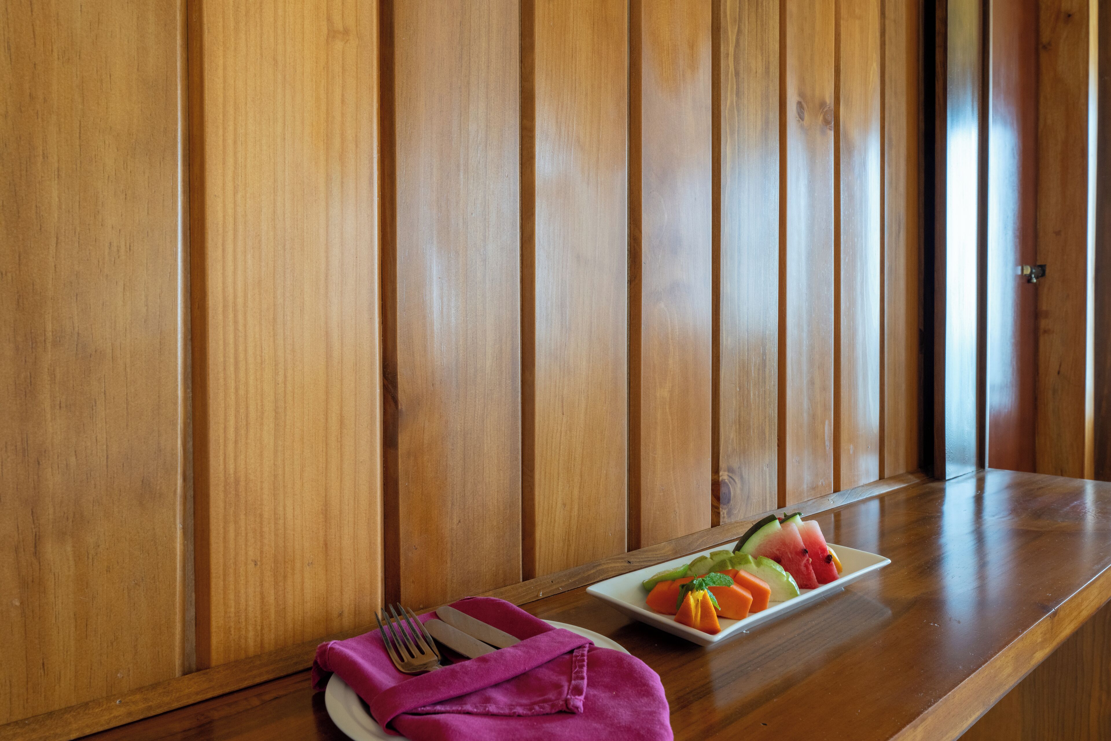Een houten tafel met een fruitschaal en een gevouwen servet.
