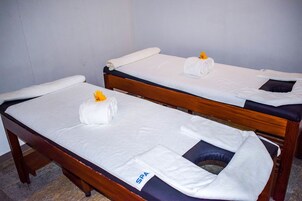 Two single beds with white linens and towels, a wooden headboard, and a spa label on the foot of one bed.