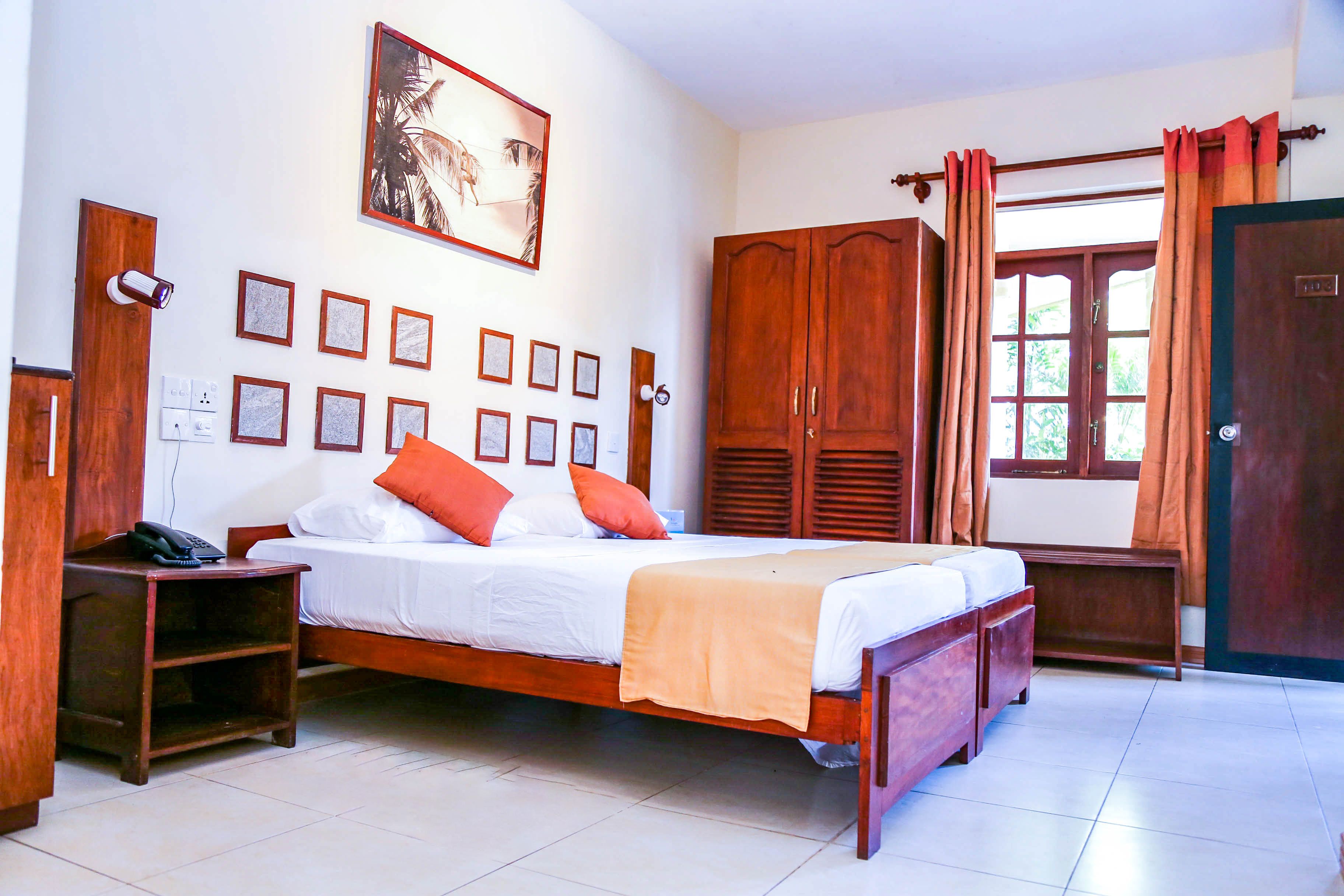 A bedroom with a bed, wooden wardrobe, bedside tables, and a wall-mounted security camera.