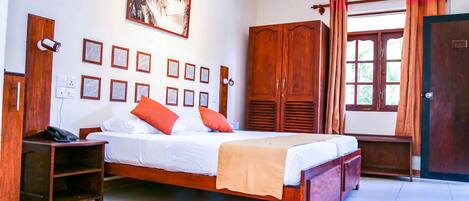 A bedroom with a bed, wooden wardrobe, bedside tables, and a wall-mounted security camera.