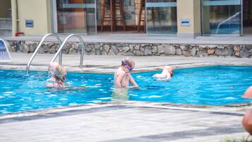 Una piscina al aire libre, sombrillas, sillones reclinables de piscina