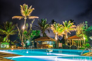 Una piscina al aire libre, sombrillas, sillones reclinables de piscina