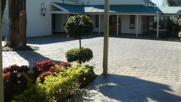 Un edificio con techo verde y un patio empedrado con un árbol y arbustos.