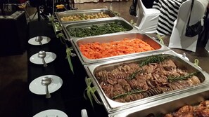 A buffet with various food options including green beans, carrots, and meat.