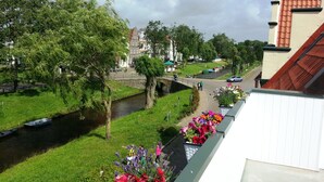 A riverside view with a bridge, greenery, and buildings in the background. - Pension Marktblick (Friedrichstadt)