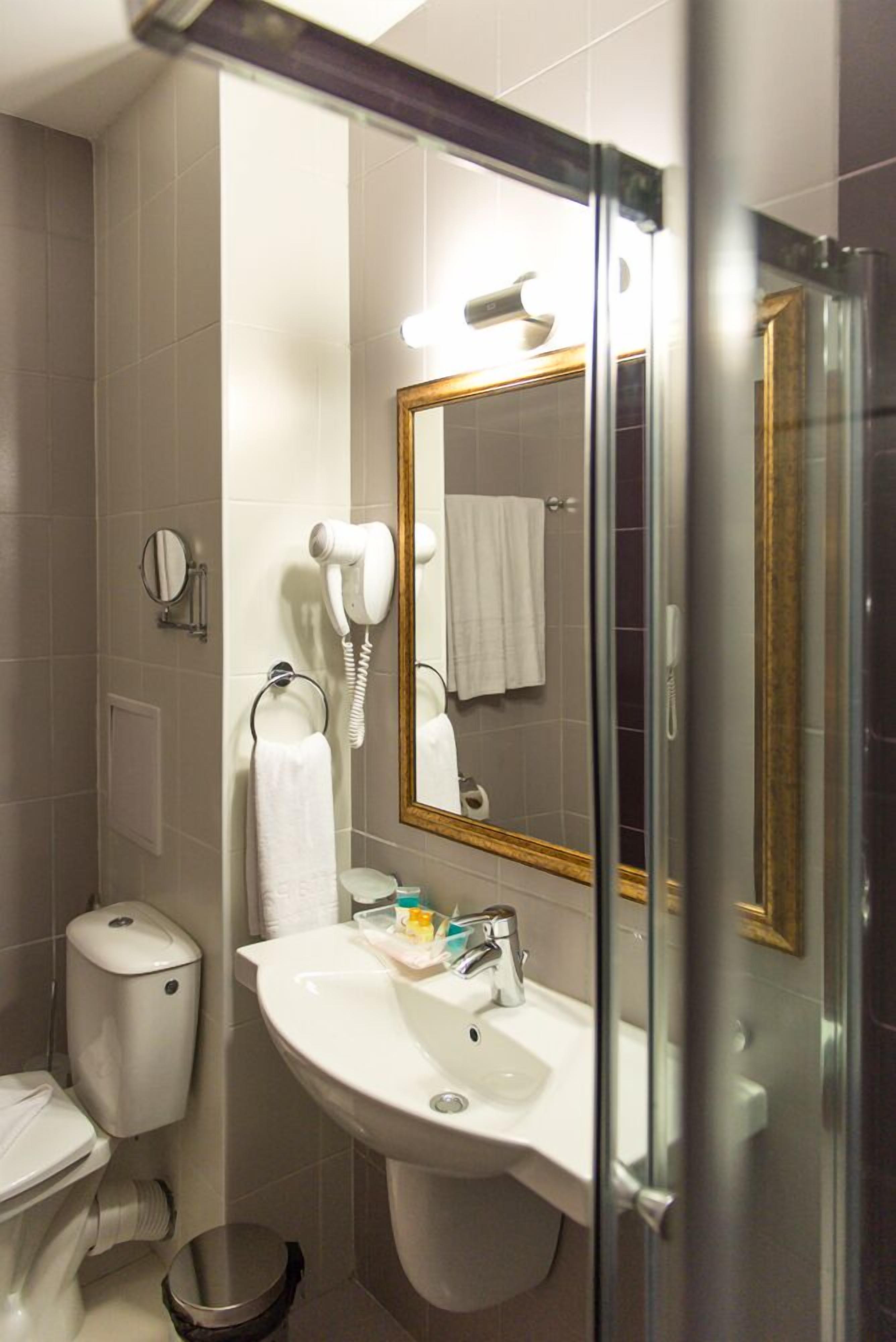 Casa de banho com sanita, lavatório com espelho, secador de cabelo e zona de duche.