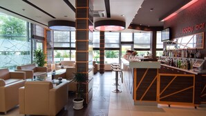 Een ontvangsthal met een bar, zitplaatsen en grote ramen.