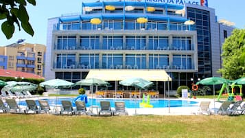 Regatta Palace Hotel features a grand entrance with a large glass windowed facade and a pool area with lounge chairs and umbrellas.