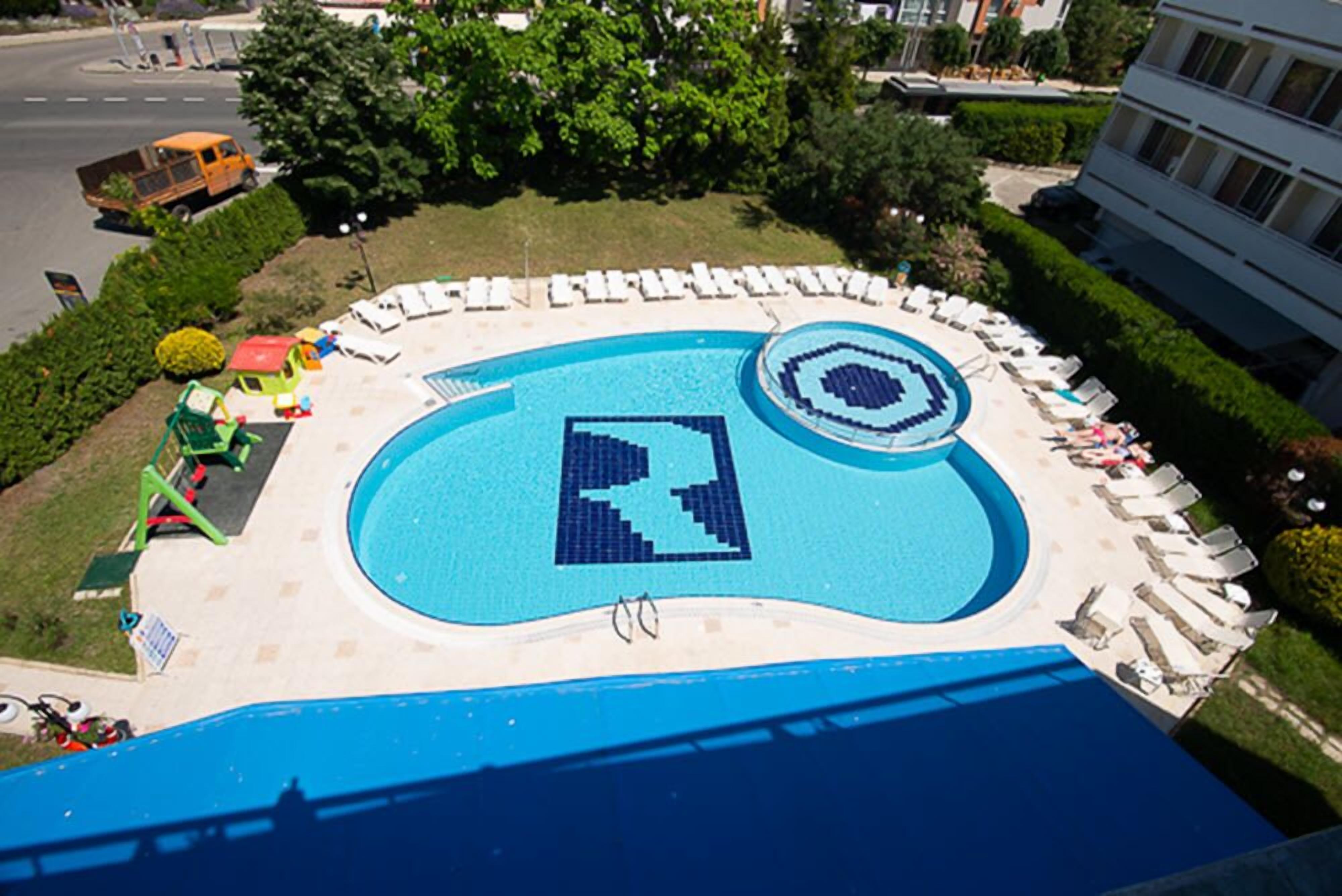 A swimming pool with a geometric design, surrounded by lounge chairs and a small play area.