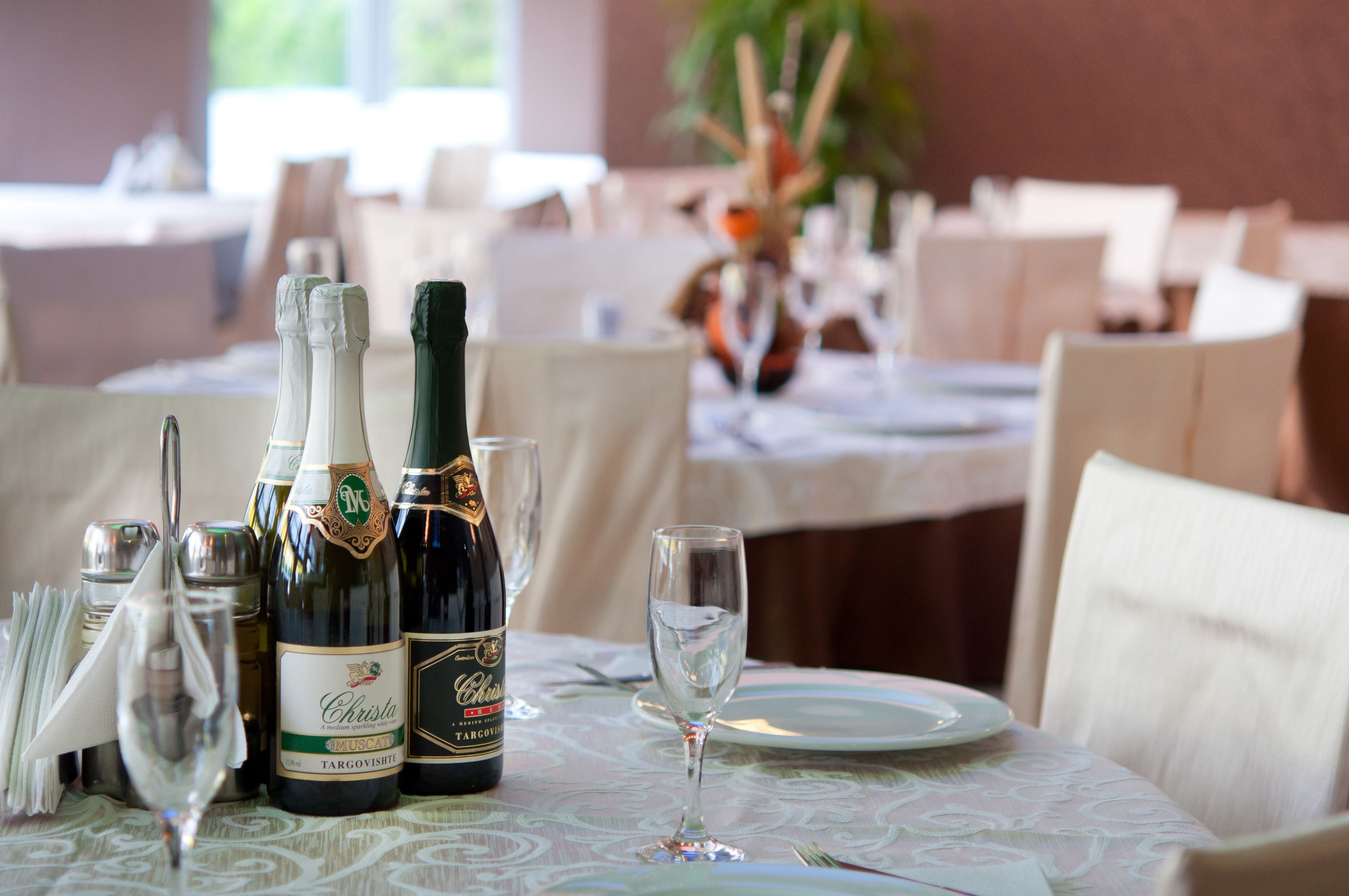 Una mesa de comedor dispuesta con botellas de vino, copas y un plato.